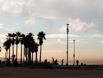 Silhouette people on beach against sky during sunset