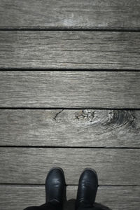 Low section of person standing on wooden floor