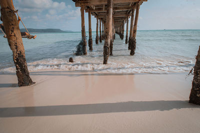 Wooden posts on beach against sky