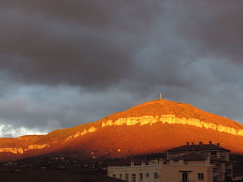 Houses on mountain against storm clouds