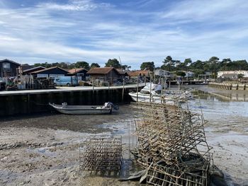 Boats moored on river by buildings against sky