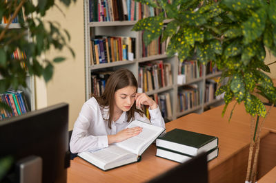 Young woman using mobile phone while sitting on table