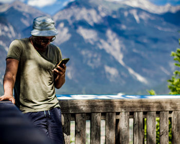 Man using mobile phone against mountains
