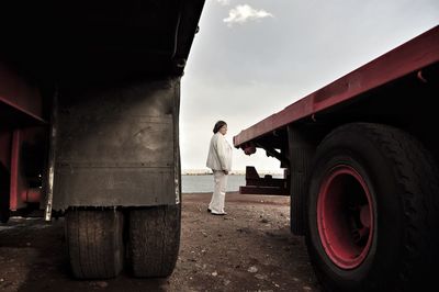 Full length of woman standing by trucks against sky