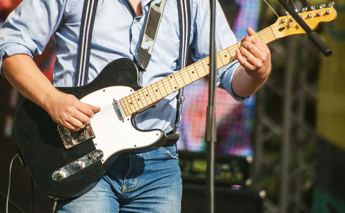 Midsection of man playing guitar at concert