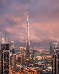 Illuminated buildings in city against sky during sunset