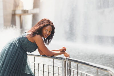 Portrait of beautiful african american woman smiling and looking away at park during sunset. 