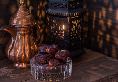 Close-up of antique teapot and lantern with raisins on table