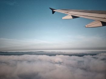 Cropped image of airplane flying over clouds