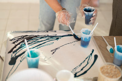 Epoxy resin  blue color for abstract art. woman hands. mixing colorful of resin in plastic cup