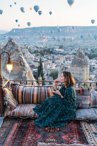 Woman drinking early morning tea with hot air balloons in cappadocia