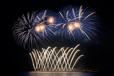 Firework display against sky at night