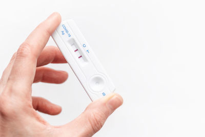 Cropped hand holding thermometer against white background