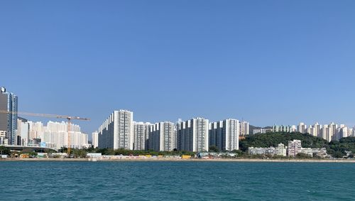 Sea by buildings against clear blue sky