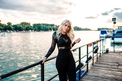 Portrait of woman standing on pier against sky