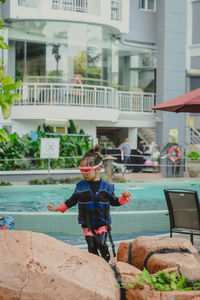 Little girl wearing life jacket walking at the swimming pool.