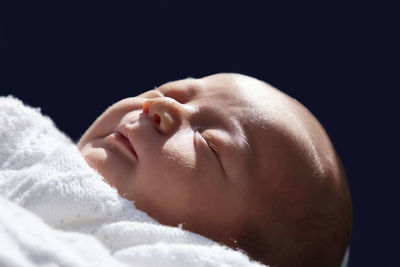 Close-up of baby boy sleeping against blue background