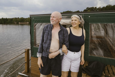 Happy senior couple standing with arm in arm on houseboat