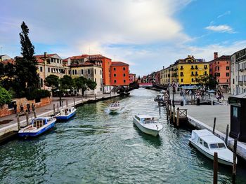 Boats moored in canal passing through city