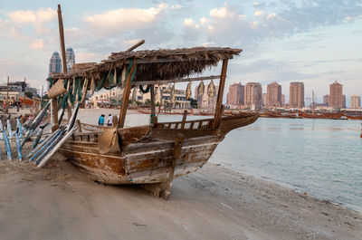 Boats moored on beach against sky in city