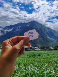 Hand holding note against mountain range