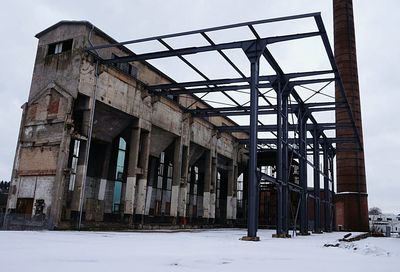 Abandoned building against sky during winter