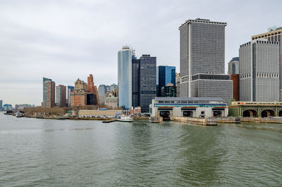 Buildings by river against cloudy sky