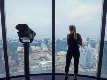 Rear view of woman at observation point looking at city from window