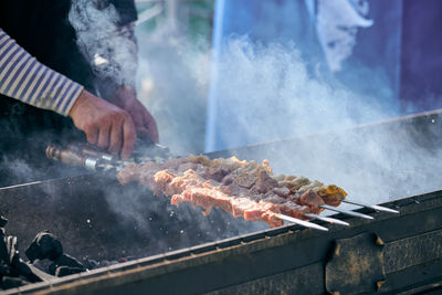 Cropped hand of man preparing food on barbecue grill