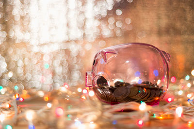 Close-up of coins in piggy bank amidst illuminated lights