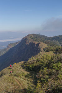 High angle view of people hiking on mountain against sky