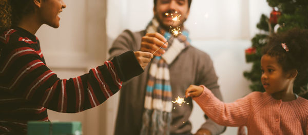 Midsection of people standing by illuminated christmas lights