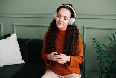 Portrait of smiling young woman sitting on bed at home