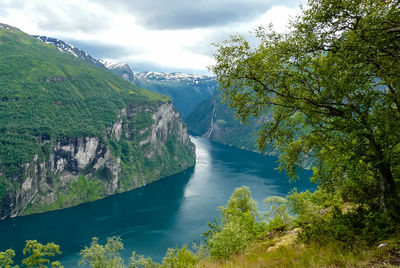 Scenic view of waterfall by trees against sky