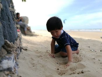 Cute boy playing with sand at beach