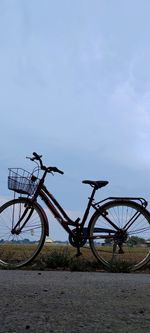 Bicycle parked by water against sky