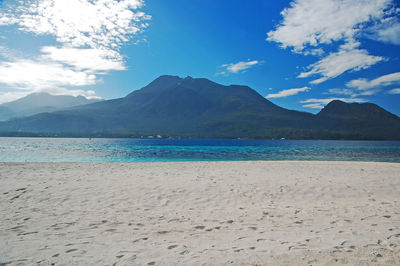 Scenic view of sea and mountains against blue sky