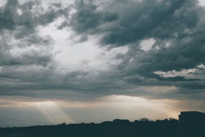 Silhouette of trees against cloudy sky