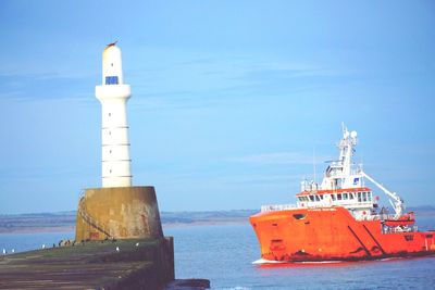 Lighthouse by sea against sky