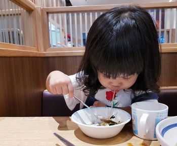 Girl having food at table in restaurant