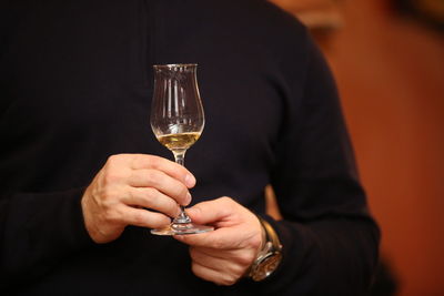 Close-up of man holding wineglass against blurred background