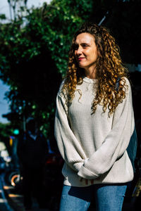 Portrait of smiling woman standing against tree