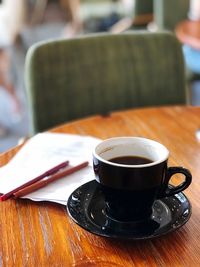 Close-up of coffee cup on table with writing materials