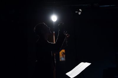 Side view of man holding illuminated lighting equipment at night