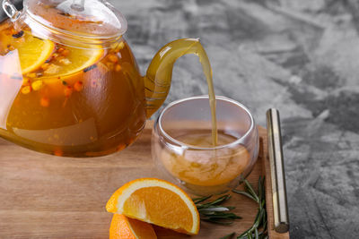 Cropped image of teapot pouring drink in drinking glass