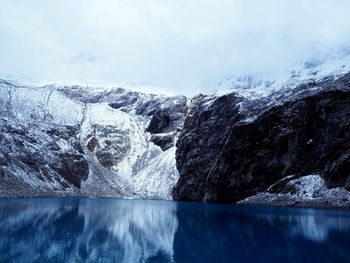 Scenic view of lake by snowcapped mountains against sky