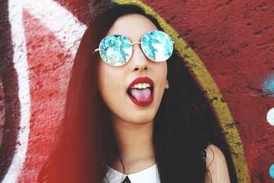 Portrait of smiling young woman against wall