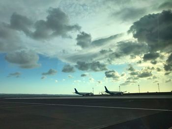 Airplane on runway against sky during sunset