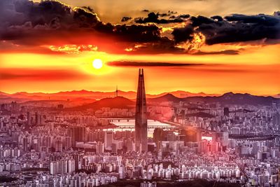 Aerial view of city against cloudy sky during sunset
