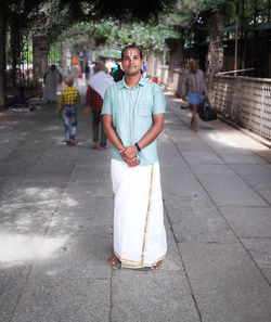Portrait of man in traditional clothing standing on footpath